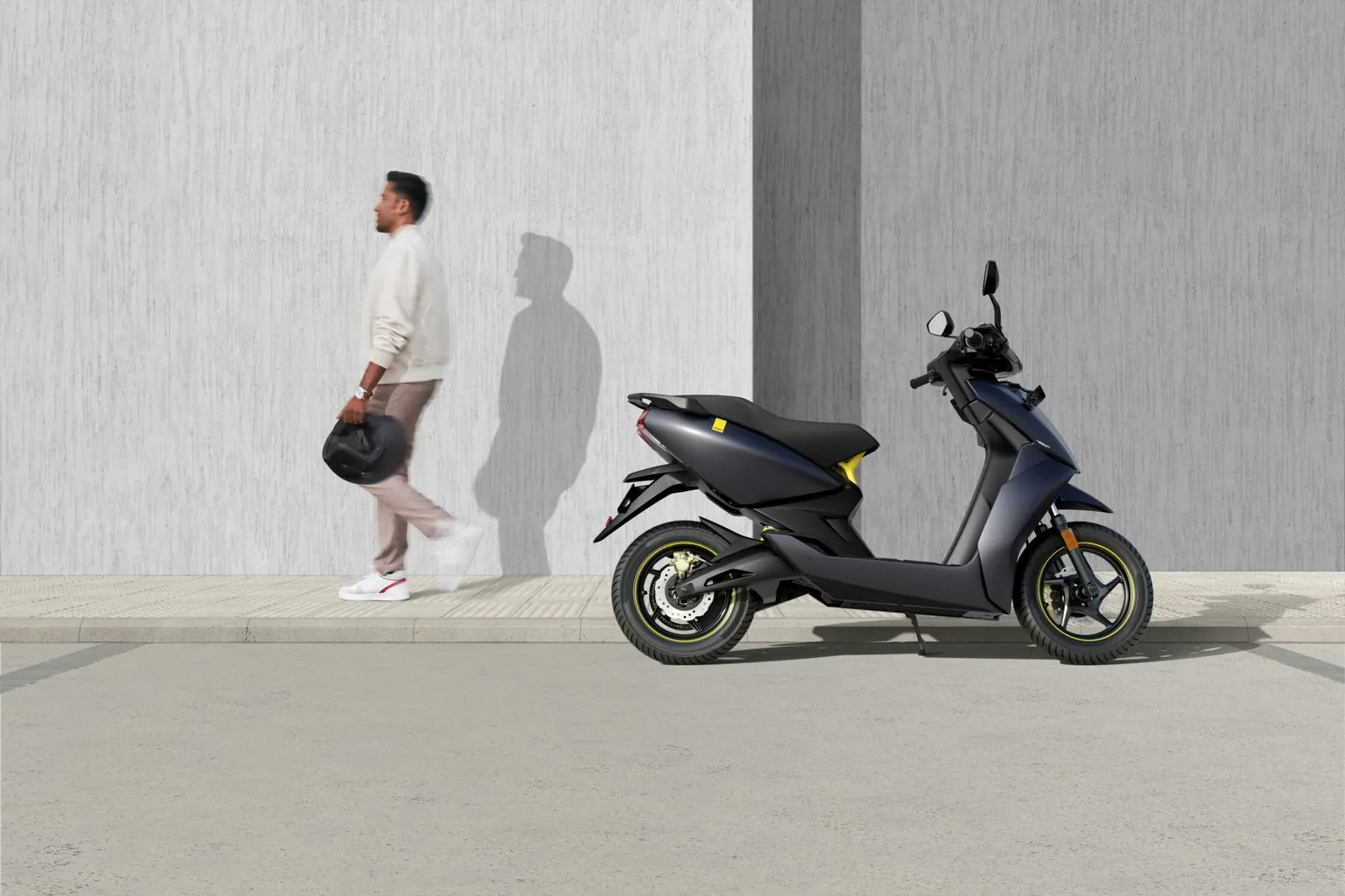 Scooter 50 cm³ garé le long d'un mur, un piéton passant à côté