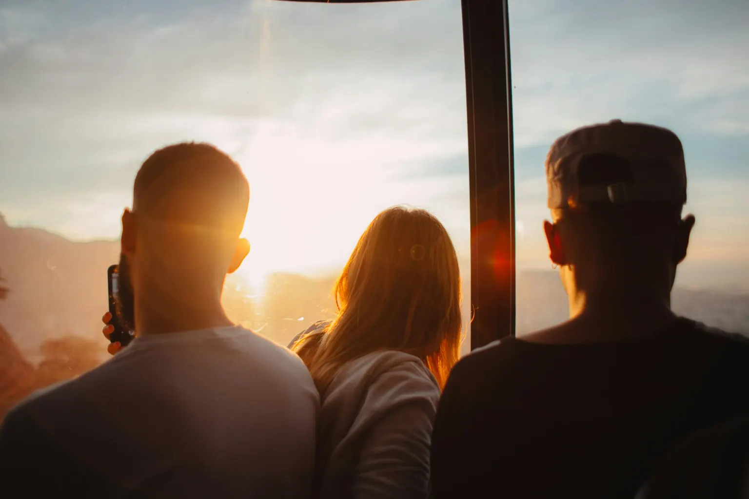 Trois jeunes de dos face au coucher de soleil