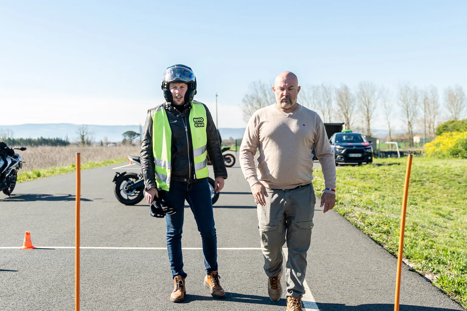 Moniteur et élève moto sur la piste de formation, plots de manœuvre en place