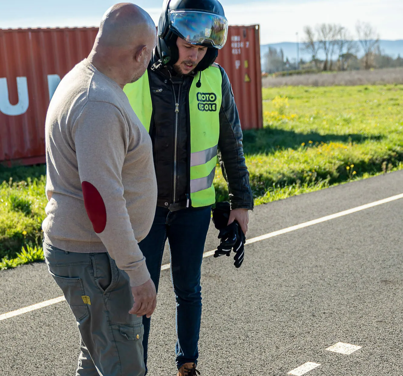 Moniteur expliquant un exercice à un élève moto en gilet de sécurité