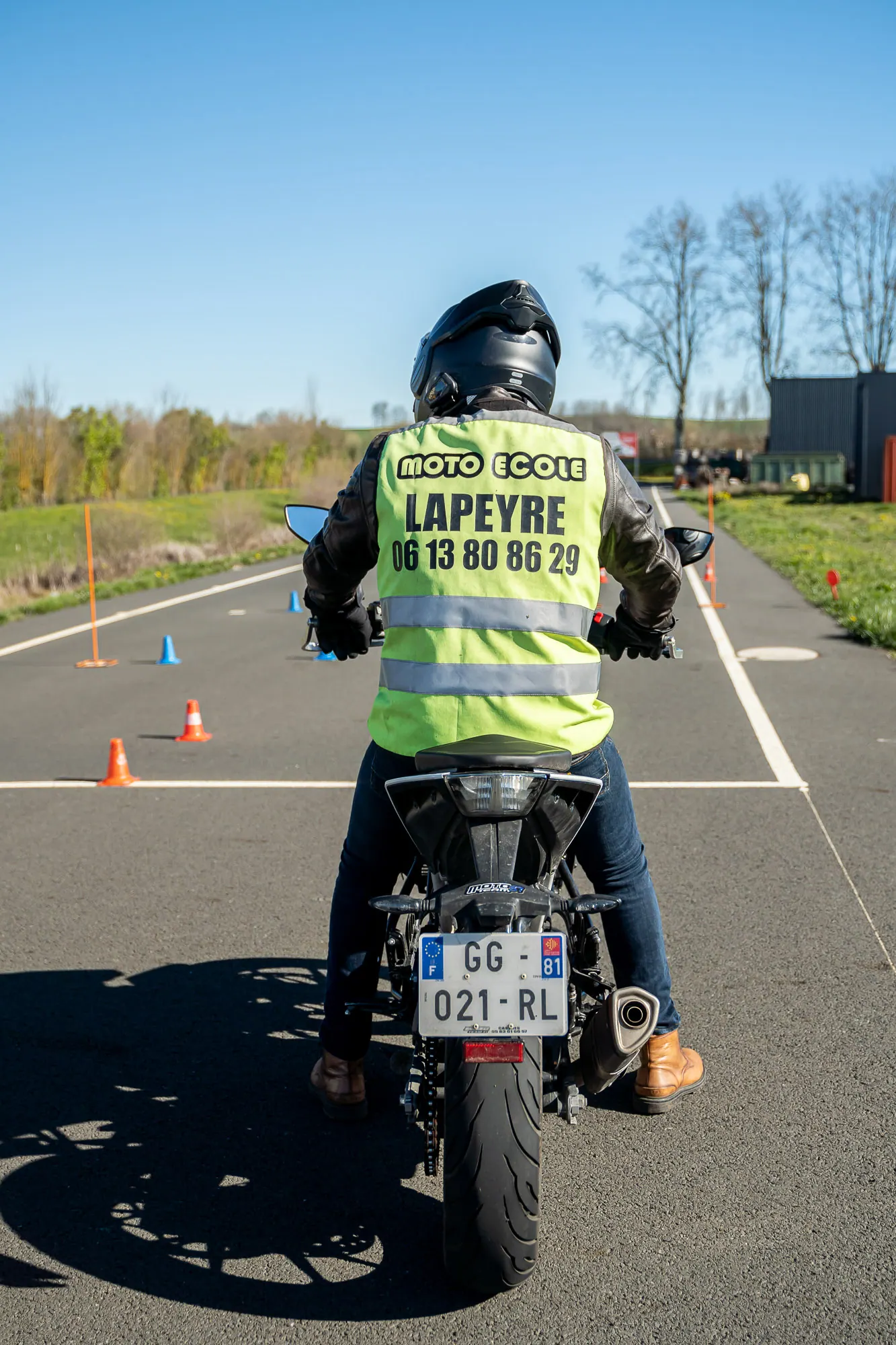 Élève moto de dos effectuant un parcours de plots sur la piste