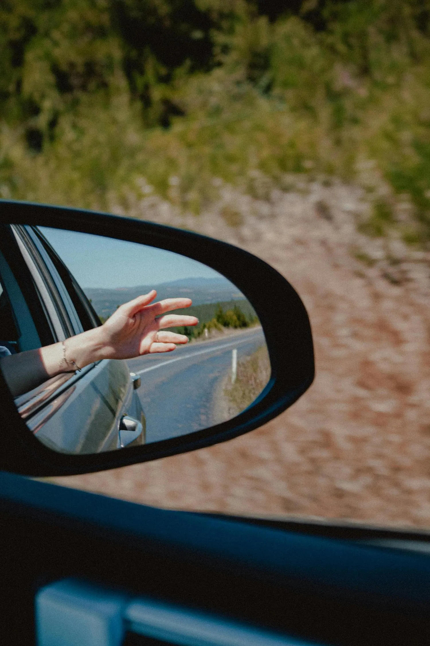 Main tendue par la vitre ouverte d’une voiture en mouvement