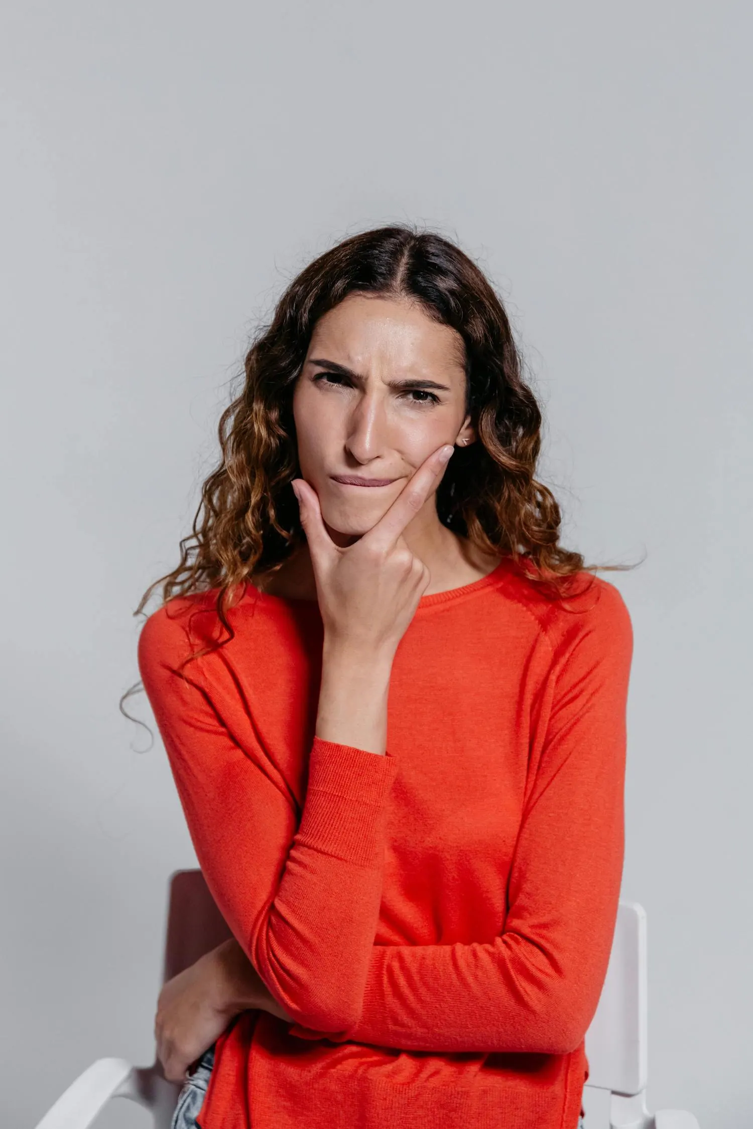 Jeune femme réfléchissant, main sur le menton